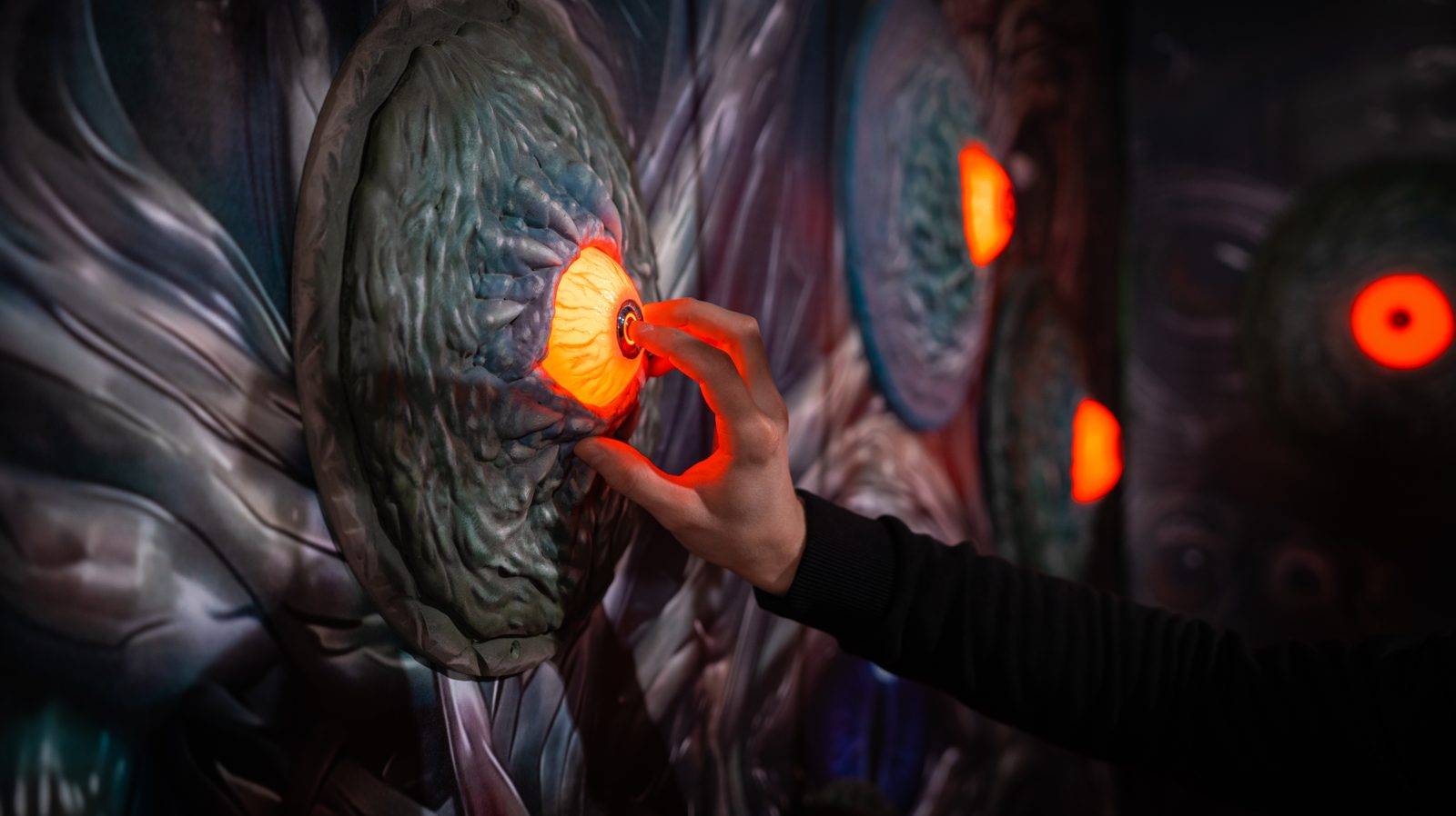 A hand presses a glowing eye button in the final monster fight