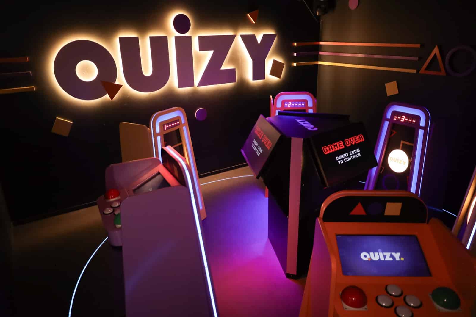 Quizy player station in front of the lit Quizy wall